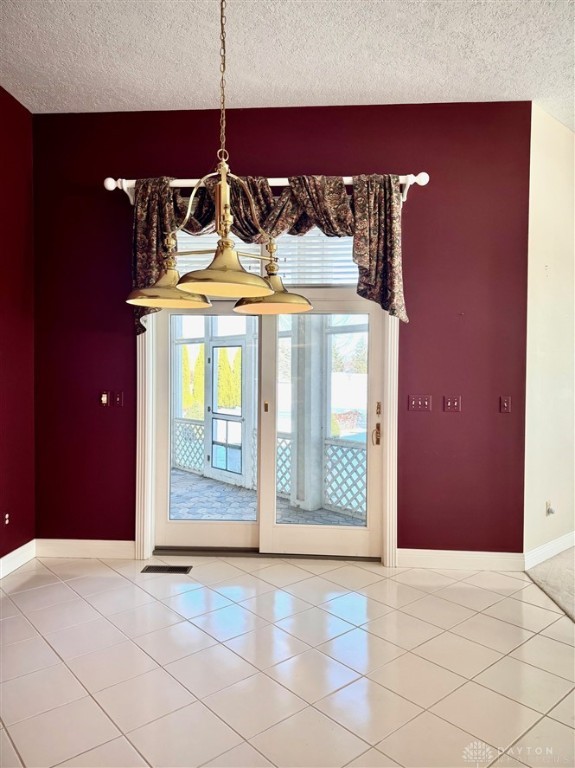 interior space with a textured ceiling and light tile patterned flooring