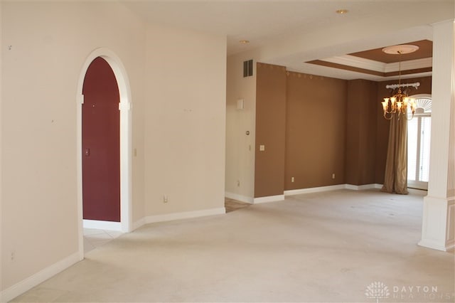 carpeted spare room with a raised ceiling, ornamental molding, and an inviting chandelier