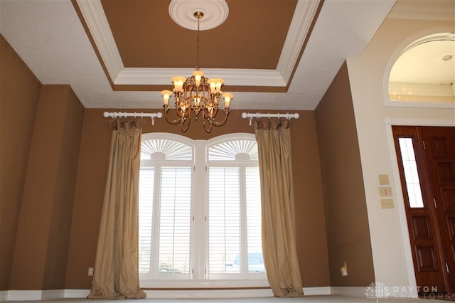 interior space featuring ornamental molding, an inviting chandelier, and a tray ceiling