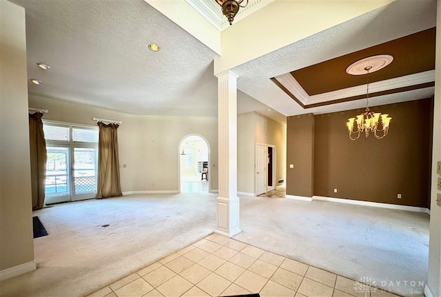 empty room with decorative columns, crown molding, and light carpet