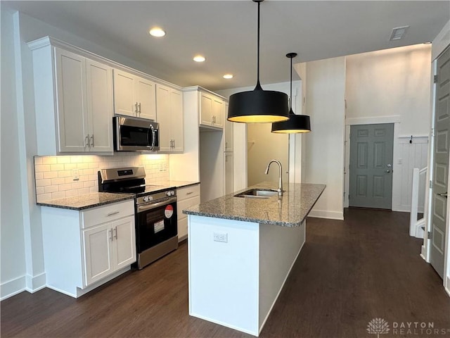 kitchen featuring stainless steel appliances, white cabinetry, dark stone counters, and decorative light fixtures