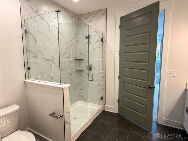 bathroom featuring toilet, vanity, tile patterned floors, and a shower with door