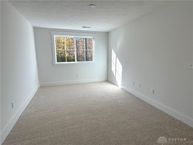 carpeted empty room with a textured ceiling