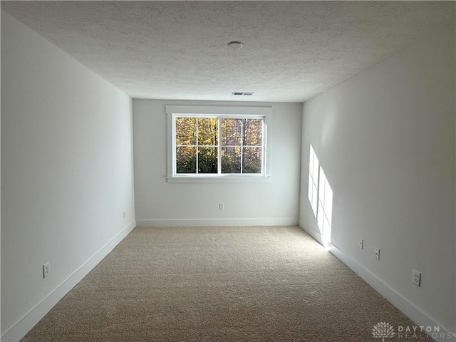 unfurnished room featuring light colored carpet and a textured ceiling