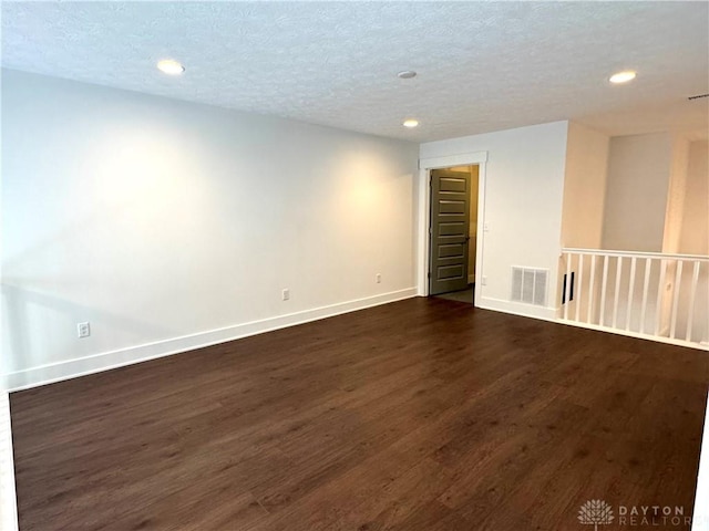 empty room with a textured ceiling and dark hardwood / wood-style floors