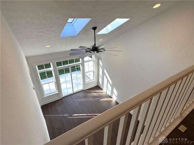 stairway featuring ceiling fan, a skylight, and hardwood / wood-style flooring