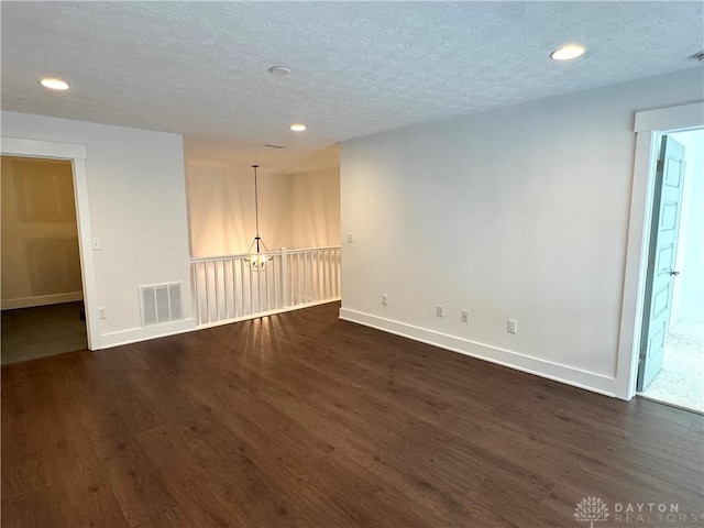 unfurnished room with a textured ceiling and dark hardwood / wood-style flooring