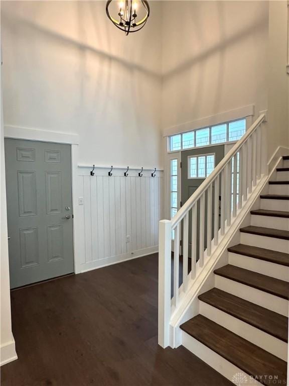 entryway featuring a towering ceiling, dark hardwood / wood-style flooring, and an inviting chandelier