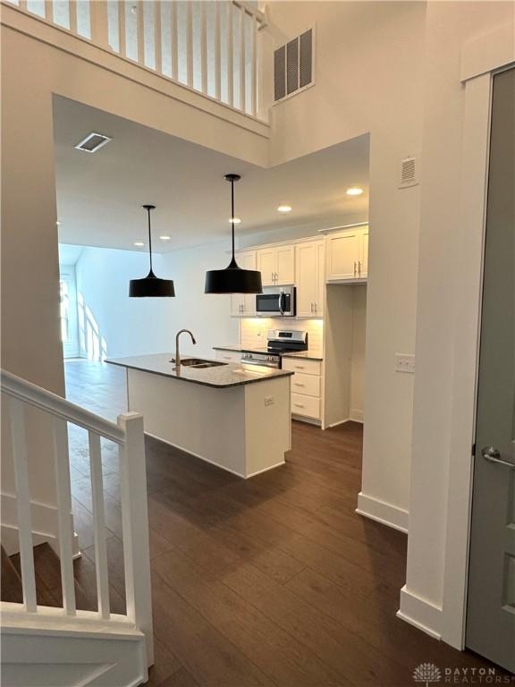 kitchen with pendant lighting, sink, appliances with stainless steel finishes, an island with sink, and white cabinets