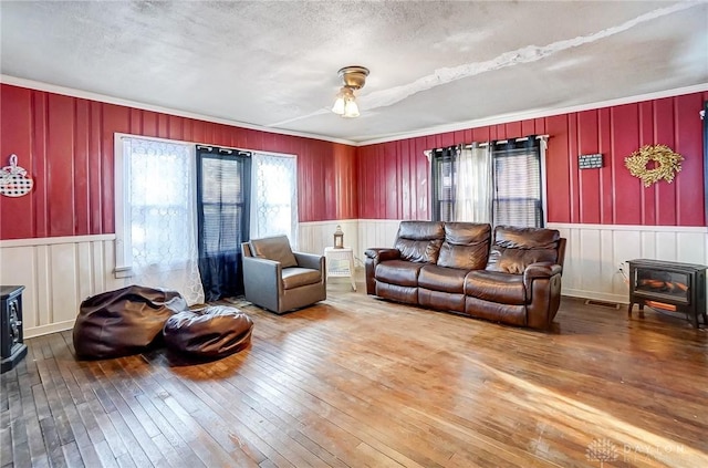 living room featuring a textured ceiling, a wood stove, and hardwood / wood-style flooring