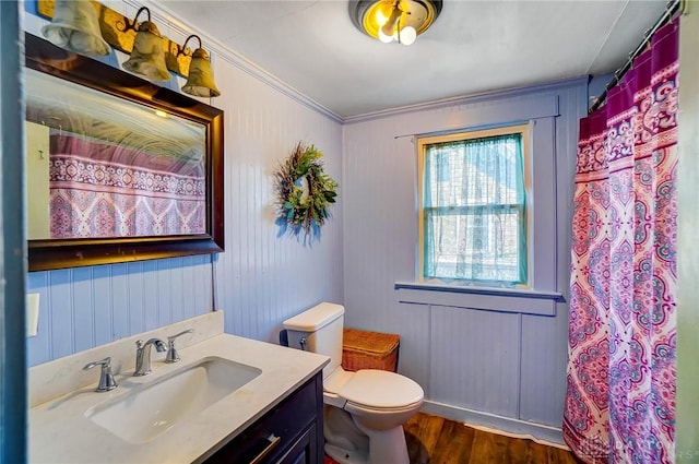 bathroom with wood-type flooring, toilet, vanity, and crown molding