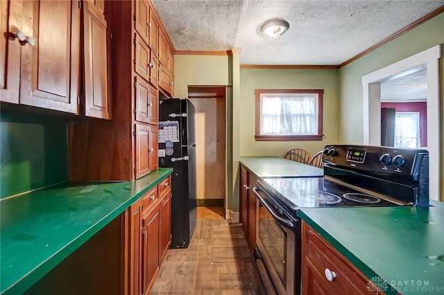 kitchen featuring electric range oven, crown molding, light wood-type flooring, a textured ceiling, and black refrigerator