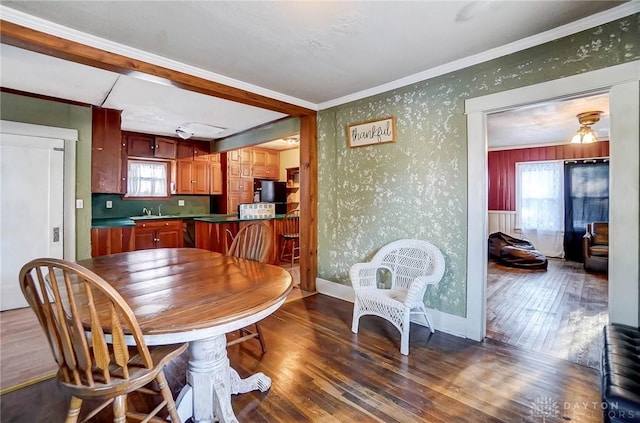 dining space featuring dark wood-type flooring, sink, and crown molding