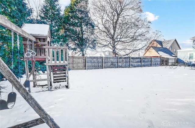 yard layered in snow featuring a playground