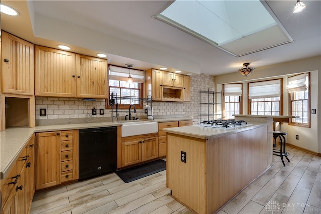 kitchen with dishwasher, a kitchen island, tasteful backsplash, sink, and gas cooktop