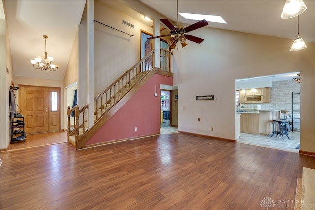 unfurnished living room with high vaulted ceiling, wood-type flooring, and ceiling fan with notable chandelier