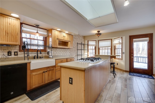 kitchen with a center island, a kitchen bar, sink, black dishwasher, and hanging light fixtures