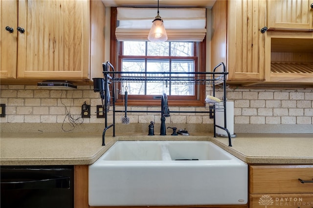 kitchen featuring black dishwasher, light brown cabinets, backsplash, pendant lighting, and sink