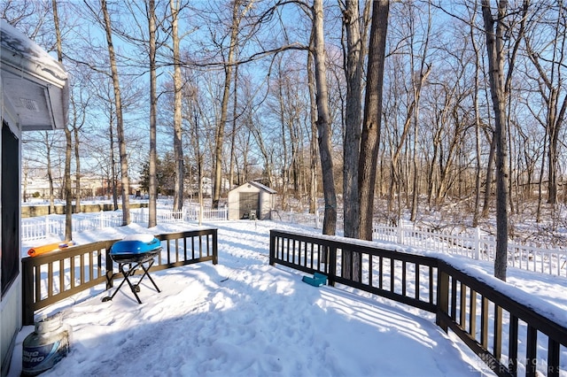 snow covered deck with area for grilling and a shed