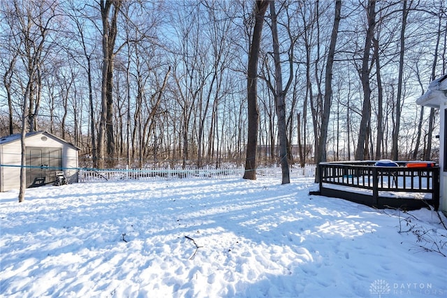 snowy yard with a deck and a storage unit