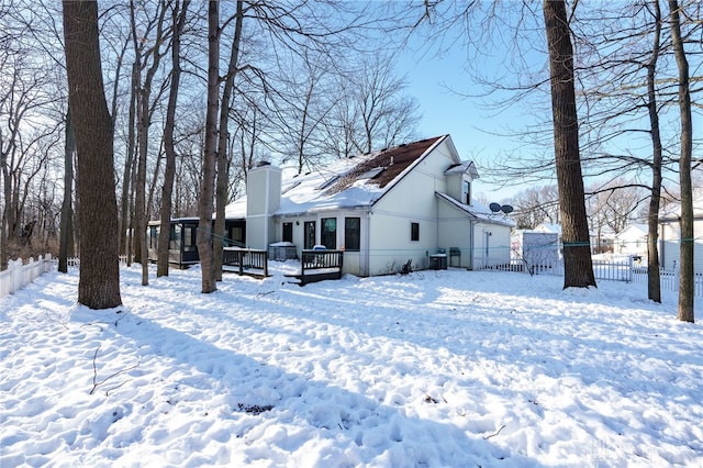 snow covered back of property featuring a deck