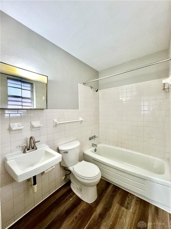 full bathroom featuring shower / washtub combination, tile walls, toilet, a sink, and wood finished floors