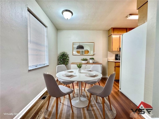 dining space with dark wood-style floors, visible vents, and baseboards