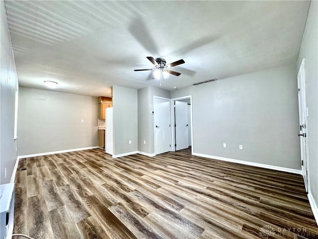 interior space featuring a ceiling fan, wood finished floors, visible vents, and baseboards