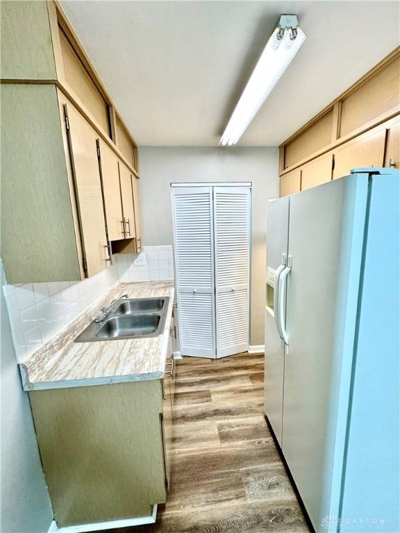 kitchen featuring light wood-style flooring, white refrigerator with ice dispenser, light countertops, and a sink