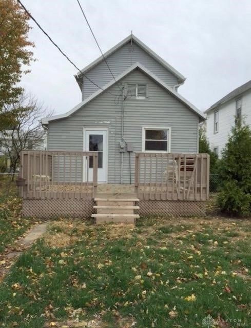 back of house with a deck and a lawn