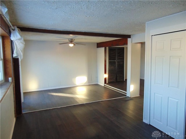 spare room with a textured ceiling, ceiling fan, dark hardwood / wood-style flooring, and beam ceiling