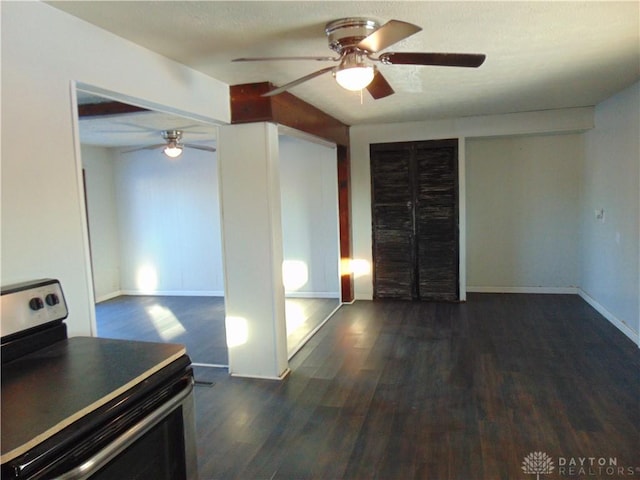 interior space featuring beam ceiling, ceiling fan, dark wood-type flooring, and stainless steel electric stove