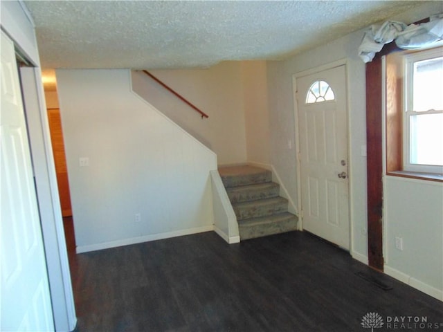 entrance foyer featuring dark wood-type flooring, a textured ceiling, and a wealth of natural light