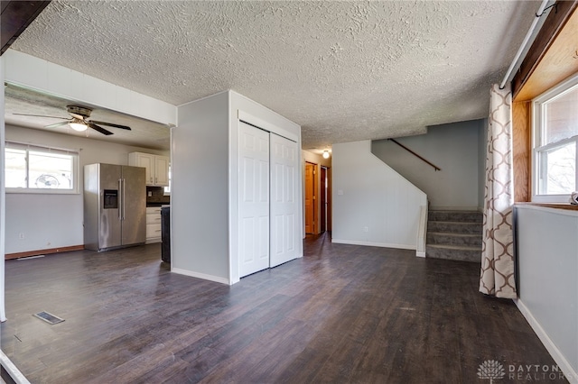 5254 Powell Rd, Dayton, OH 45424 - unfurnished living room featuring dark wood finished floors, baseboards, plenty of natural light, stairs, and a textured ceiling