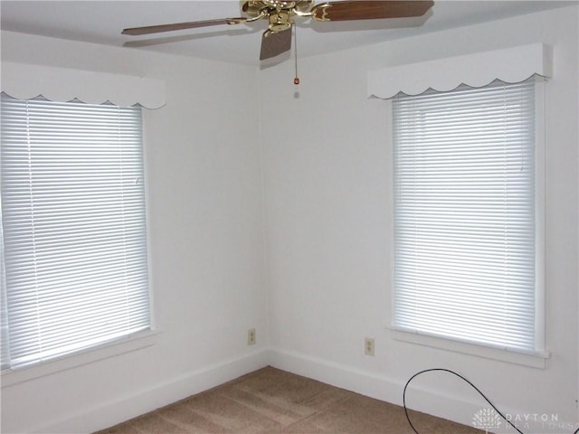 empty room featuring ceiling fan, a healthy amount of sunlight, and light colored carpet