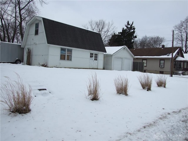 snow covered back of property with an outbuilding