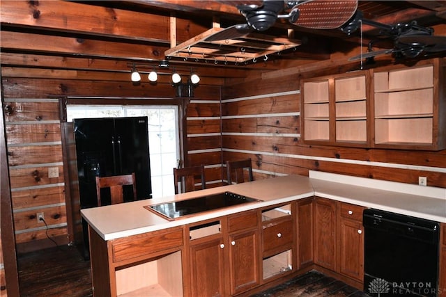 kitchen featuring ceiling fan, black appliances, kitchen peninsula, and wooden walls