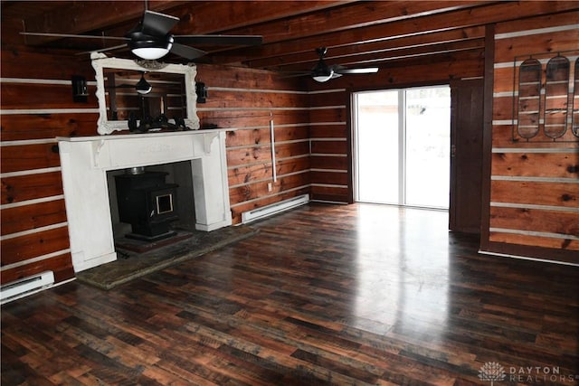 unfurnished living room with wood walls, a baseboard heating unit, ceiling fan, a wood stove, and dark hardwood / wood-style floors