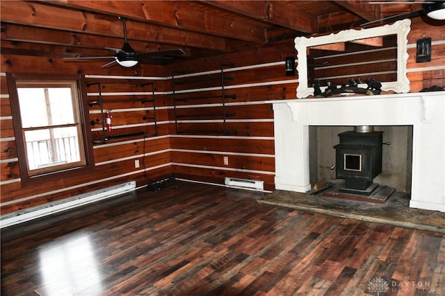 unfurnished living room featuring dark wood-type flooring, ceiling fan, a wood stove, and wood walls