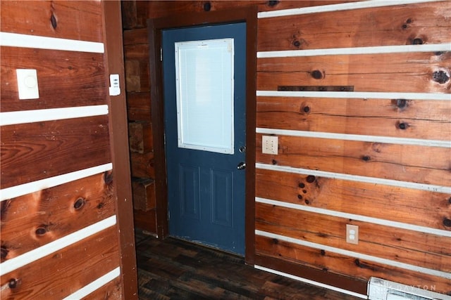 entryway featuring dark hardwood / wood-style floors and wooden walls