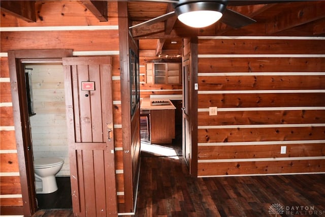 hallway featuring dark wood-type flooring and wood walls