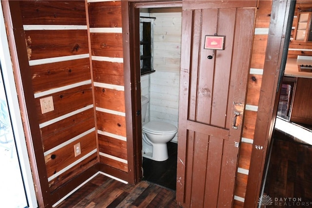 bathroom with toilet, wooden walls, and hardwood / wood-style flooring