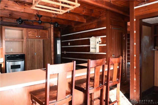 dining space featuring beam ceiling, wood ceiling, and wooden walls