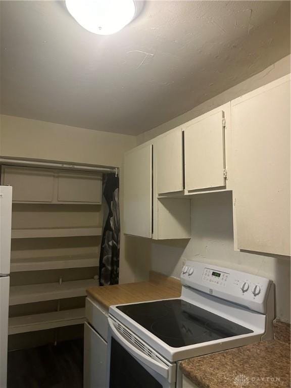 kitchen with electric stove and white cabinetry