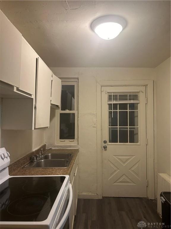 kitchen featuring white cabinetry, sink, dark wood-type flooring, white electric stove, and radiator heating unit