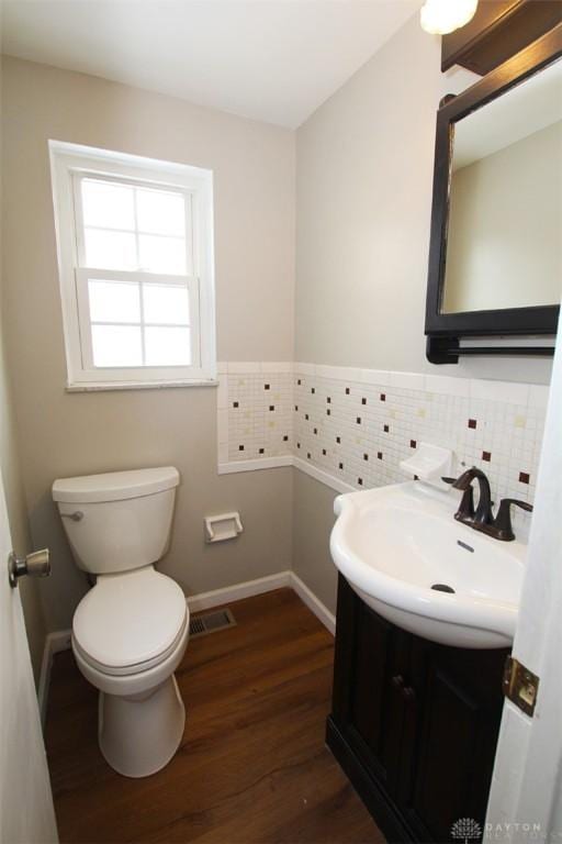 bathroom with toilet, vanity, wood-type flooring, and decorative backsplash