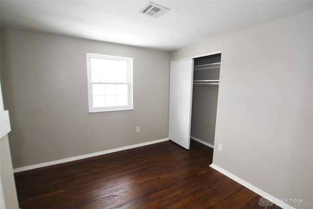 unfurnished bedroom with a closet and dark wood-type flooring