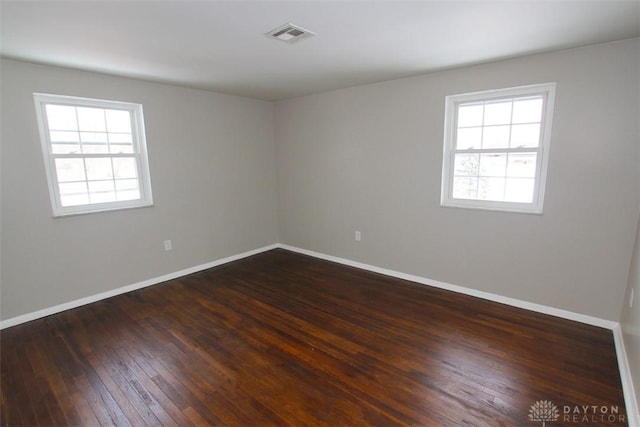 spare room featuring dark hardwood / wood-style flooring and a healthy amount of sunlight