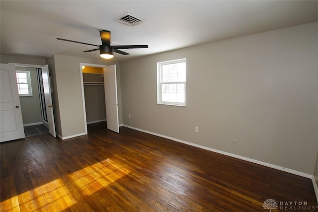 unfurnished bedroom with ceiling fan, dark wood-type flooring, and multiple windows