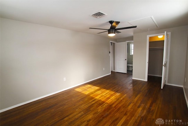 unfurnished bedroom with ceiling fan, a walk in closet, a closet, and dark hardwood / wood-style flooring